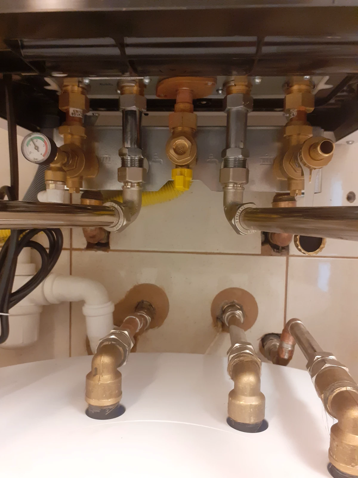 Podłączenia hydrauliczno-gazowe kotła CO z miedzianymi rurami, zaworami, manometrem i elastyczną wężownicą